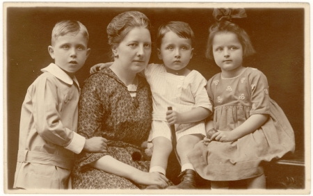 Sepia-toned portrait photograph of a woman with three young children, posing closely together in formal dress.