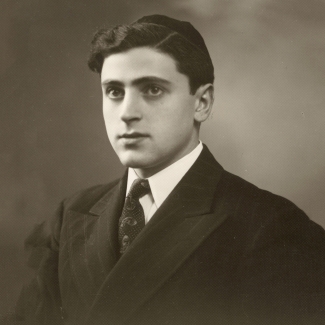 Portrait photographique en noir et blanc d'un homme en costume et cravate, regardant vers la gauche de la caméra. Il porte une kippa sur la tête.