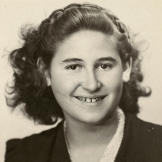 Photo de passeport en noir et blanc d'un jeune adolescente souriant à la caméra. Elle a des cheveux bruns ondulés jusqu'aux épaules.
