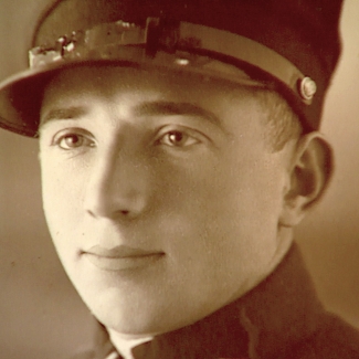 Sepia-toned photograph depicting the close-up of a man’s face. The man looks to the left of the camera, wearing what appears to be a military uniform.