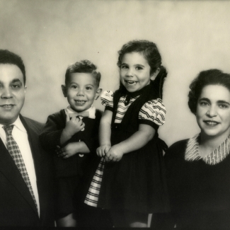 Photo en noir et blanc d'un homme et d'une femme avec deux jeunes enfants, tous souriant à la caméra.