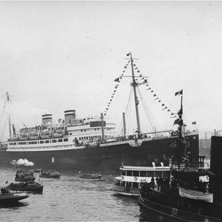 Black and white photograph of a passenger ship surrounded by smaller boats.
