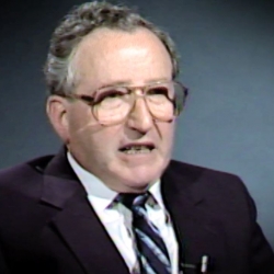 Screenshot of Holocaust survivor Moishe Kantorowitz video testimony. He is sitting in front of a dark background, and looking to the left of the camera. The camera shows his face and shoulders.