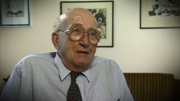 Screenshot of Holocaust survivor Gerhart Maass video testimony. He is sitting in front of a wall with three paintings, and looking to the right of the camera. The camera shows his face and shoulders.
