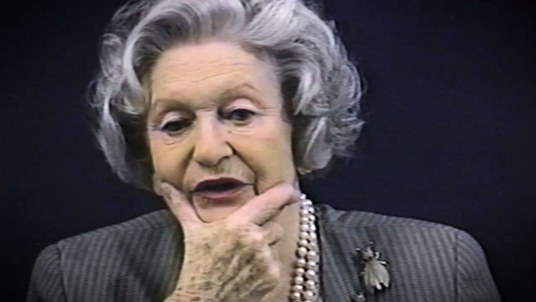 Capture d'écran du témoignage vidéo de la survivante de l’Holocauste Irene Burstyn, assise devant un fond noir, et regardant à la gauche de la caméra. Son visage et ses épaules sont visibles à la caméra.