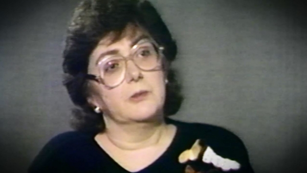 Capture d'écran de Freda Shiel, survivante de l'Holocauste, assise devant un fond gris et regardant à la droite de la caméra durant l'enregistrement de son témoignage. Son visage et ses épaules sont visibles à la caméra.
