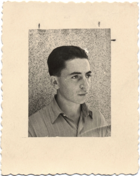 Photo en noir et blanc avec une grande bordure blanche d'un jeune homme regardant à droite de la caméra. Ses cheveux sont coiffés vers l'arrière et il porte une chemise à col.