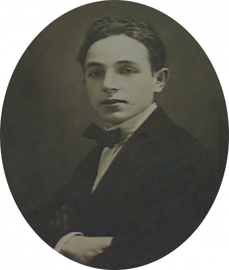 Black-and-white oval-shaped studio photograph of a young man. The man wears a suit with a bowtie. The photograph has a large white border.