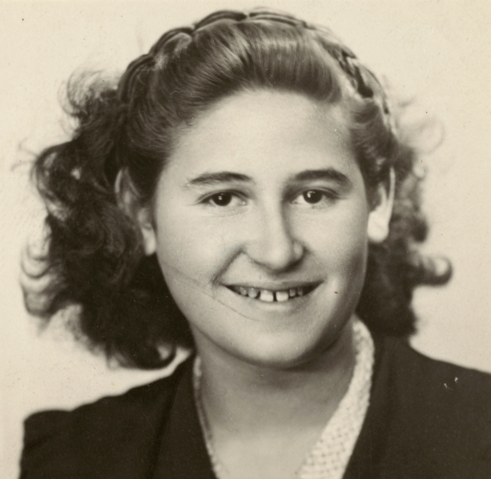 Photo de passeport en noir et blanc d'un jeune adolescente souriant à la caméra. Elle a des cheveux bruns ondulés jusqu'aux épaules.