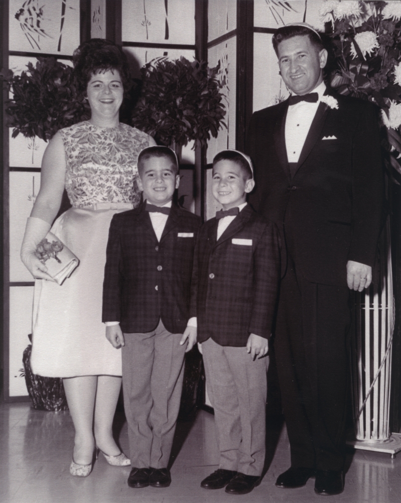 Photo en noir et blanc d'un homme et d'une femme avec leurs deux fils. La famille est vêtue de manière formelle et l'homme ainsi que les garçons portent des complets avec des nœuds papillons et la femme porte une robe.