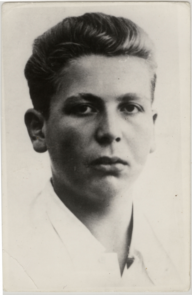 Portrait photographique d'un jeune homme, âgé d'environ 15 ans. Le jeune homme porte un chemise blanche à col et a les cheveux coiffés vers l'arrière. Il regarde directement la caméra et ne sourit pas.