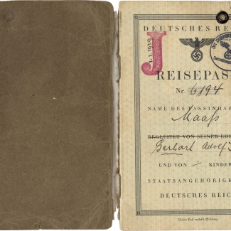 Two pages of a passport . The passport’s first page, on the right, is stamped with a red "J" and date 1/1/1939, and a circular ink stamp from the Police President of Hamburg and another green circular ink stamp. There is handwriting along the border of the page.