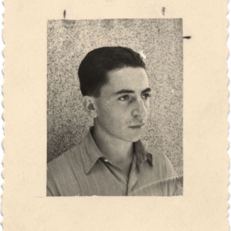 Photo en noir et blanc avec une grande bordure blanche d'un jeune homme regardant à droite de la caméra. Ses cheveux sont coiffés vers l'arrière et il porte une chemise à col.