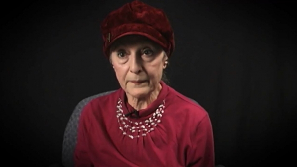 Screenshot of Holocaust survivor Sarah Engelhard video testimony. She is sitting in front of a black background, and looking to the left of the camera. The camera shows her face and shoulders.