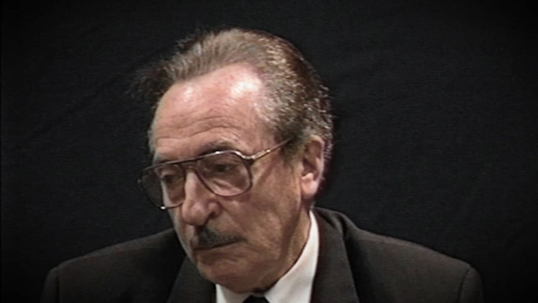 Screenshot of Holocaust survivor Michael Kutz video testimony. He is sitting in front of a black background, and looking to the left of the camera. The camera shows his face and shoulders.